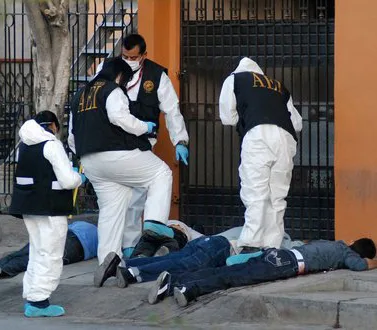 Police examine bodies after a shoot-out between drug cartel members.